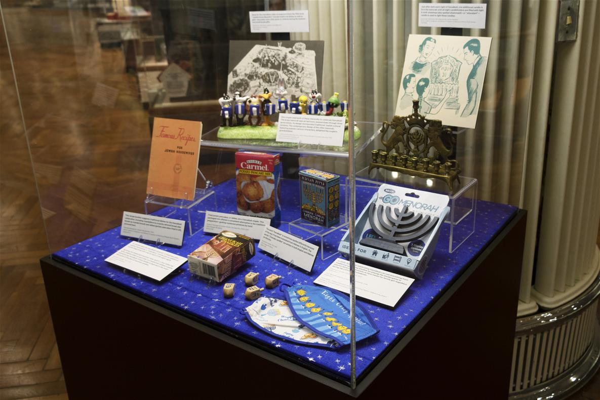 Display case with dark base and clear cover, containing various items on lucite display stands and cards with text on them