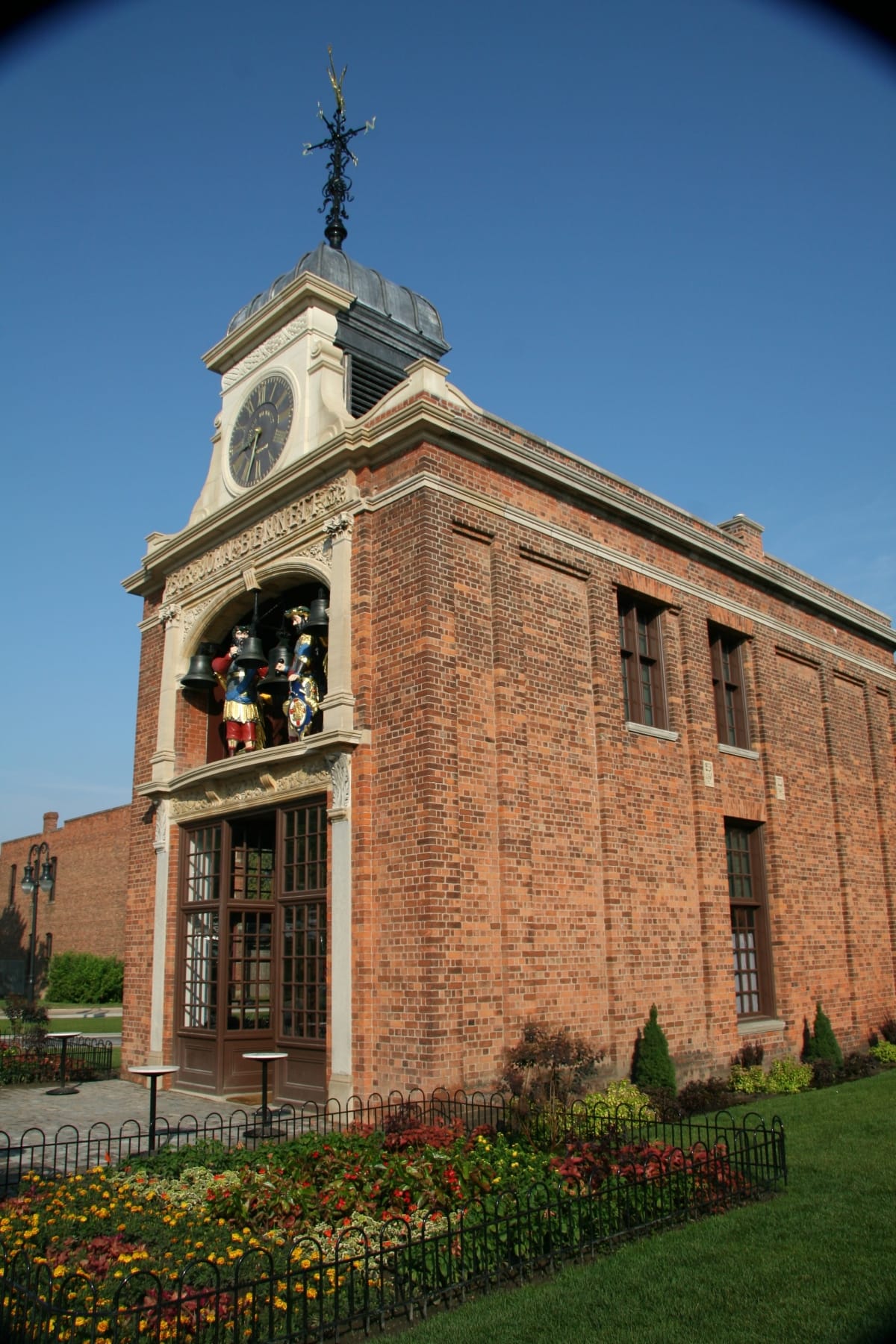 Narrow, two-story brick building with facade featuring oversize figures and a clock