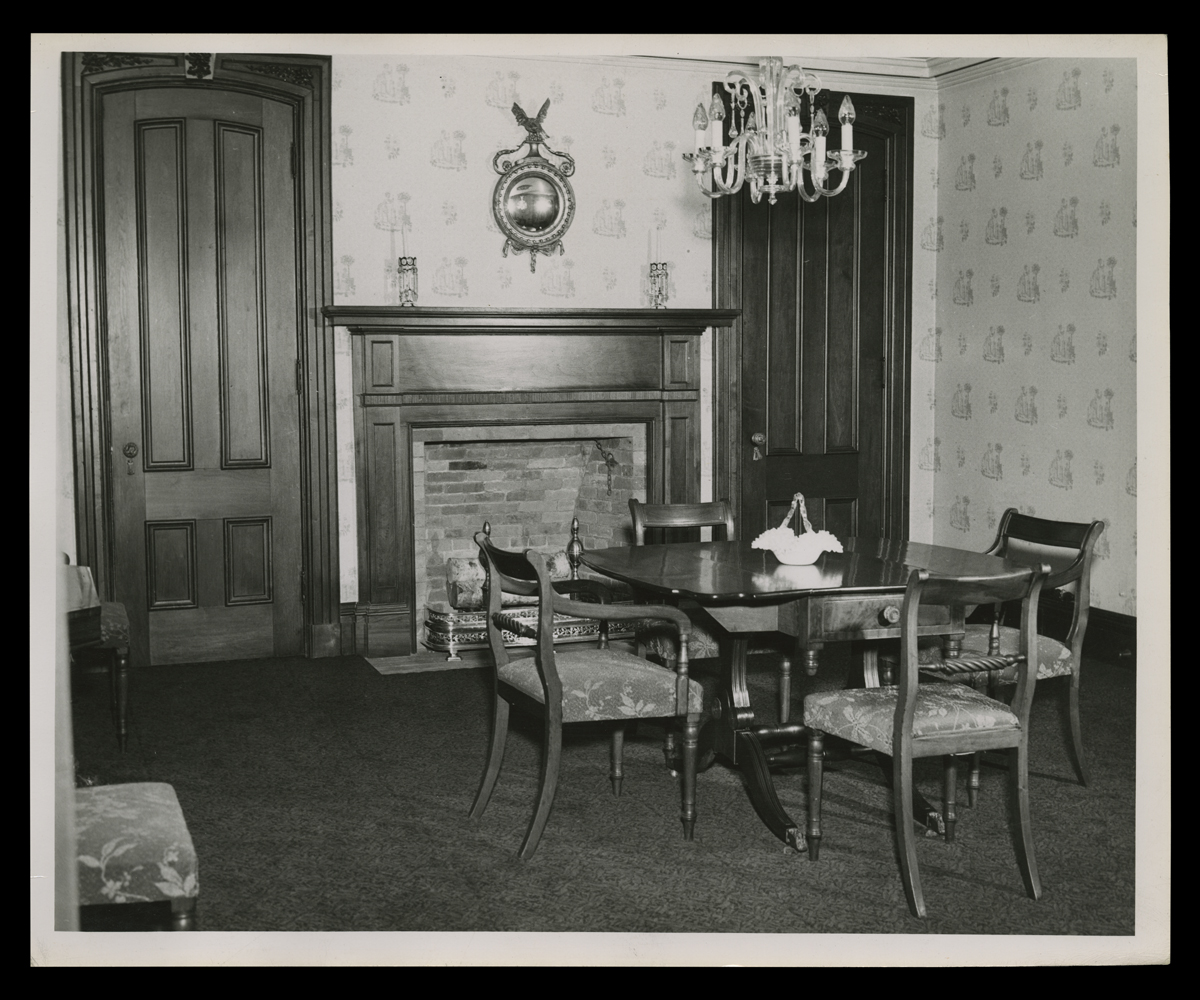 Room with table and four chairs, as well as fireplace with doors on either side, 