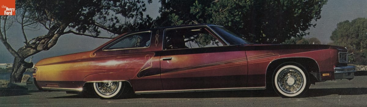 Long, low maroon and gold car with pinstriping in decorative pattern along side