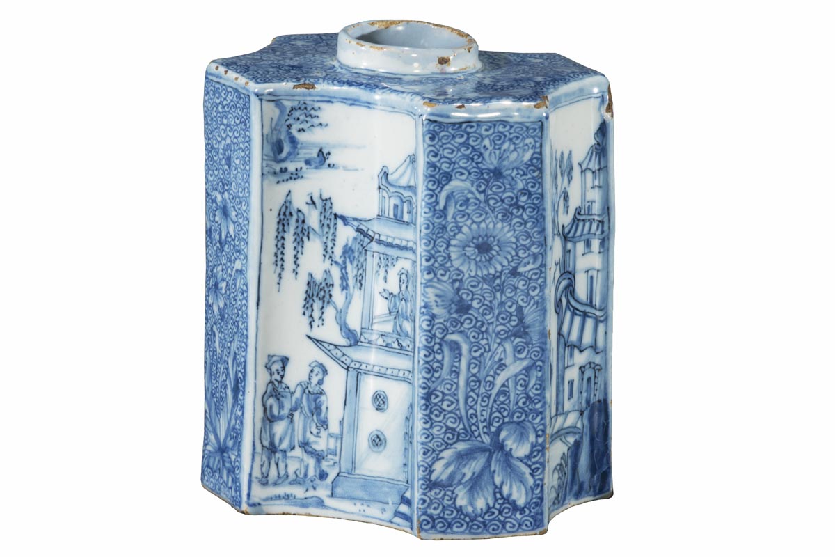 Unusually shaped white jar with blue decorations of flowers, vegetation, people, and buildings
