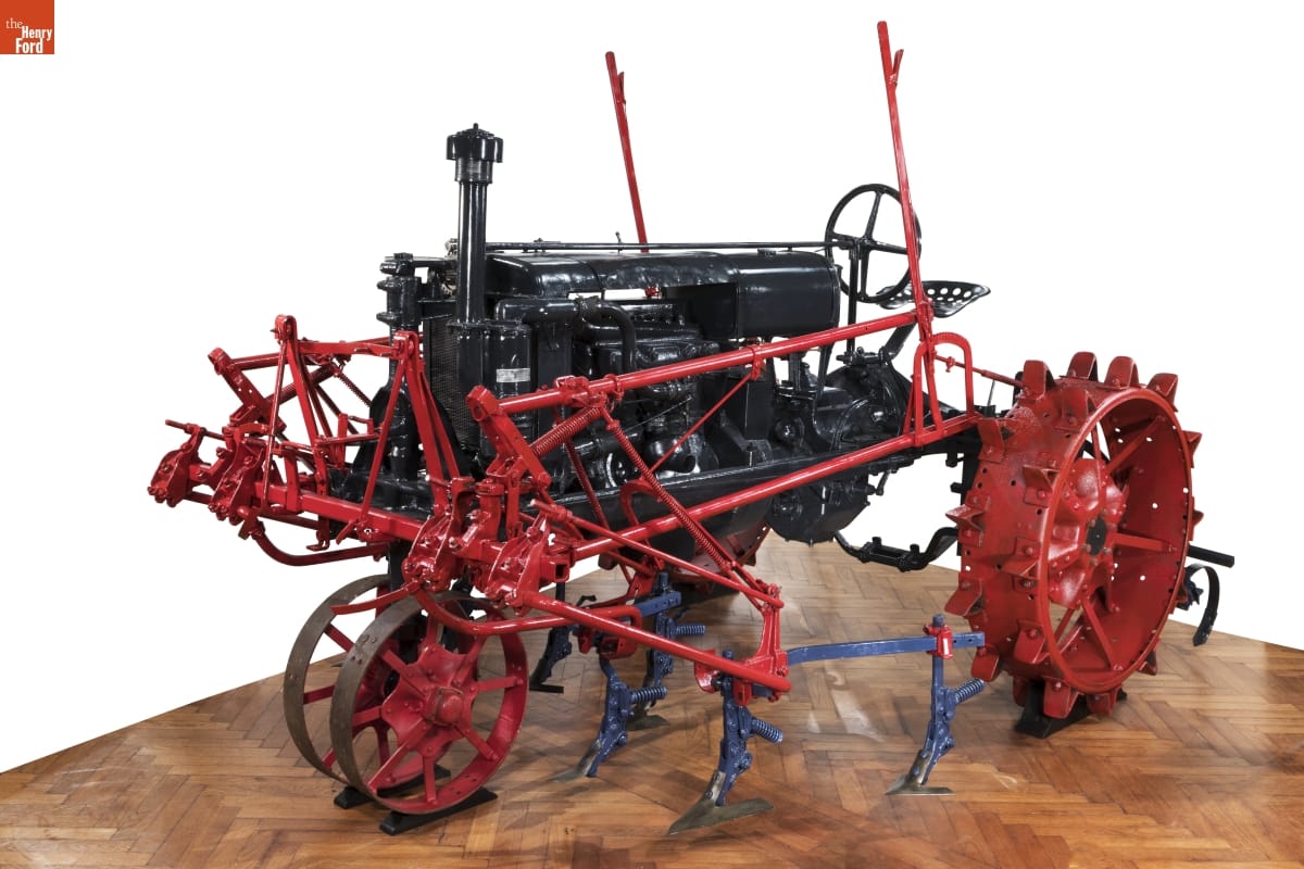 Gray tractor with red wheels and attachments along side and front