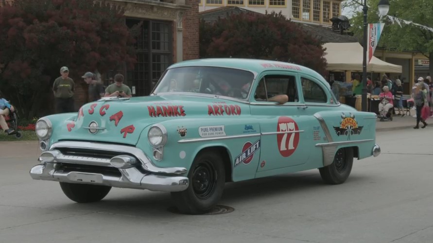 Turquoise car with text and logos on body and hood