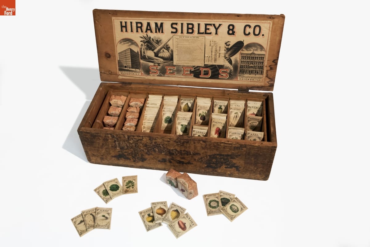 Wooden box with lid flipped back, text and images inside lid, packets inside box and some outside box
