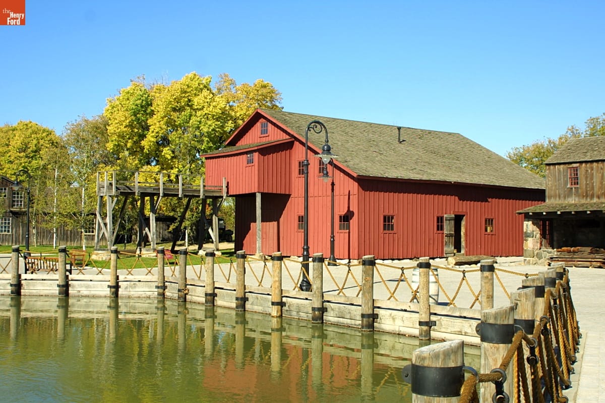 Red wooden building among other buildings by a pond