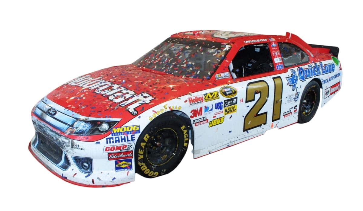 Red car with white sides with text and logos on all surfaces, covered in confetti