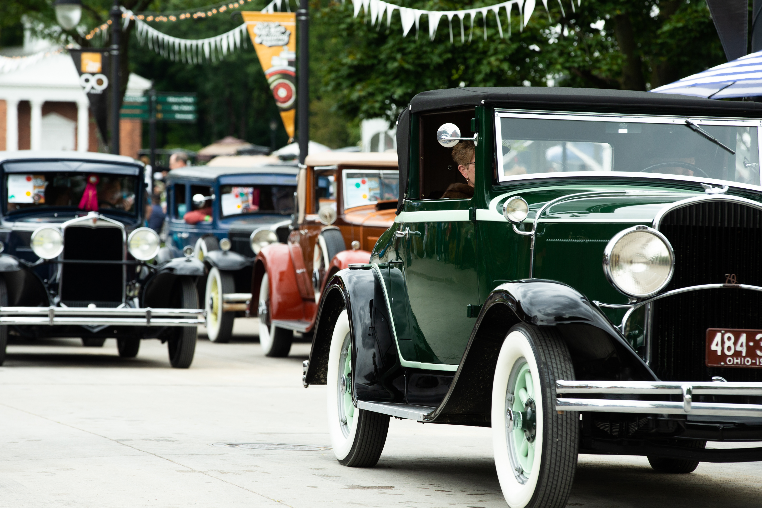Antique cars driving along concrete road