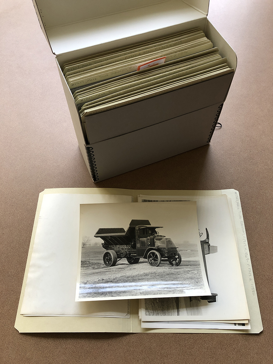 box standing vertically; folder open in front of it with photo lying on top