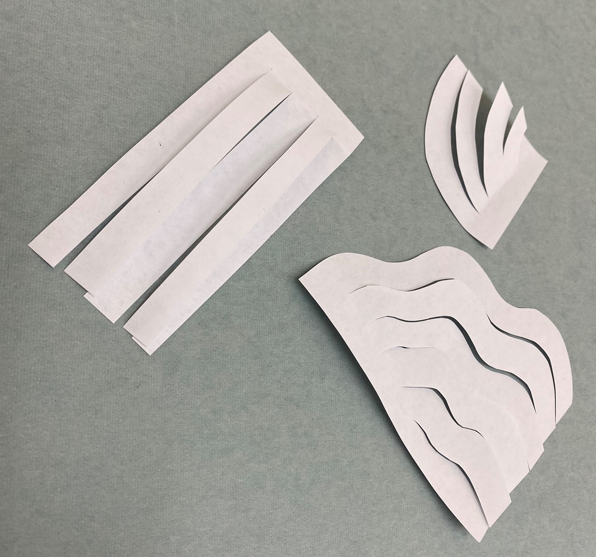 White paper cut into straight strips, half-arc strips, and wavy half-arc strips