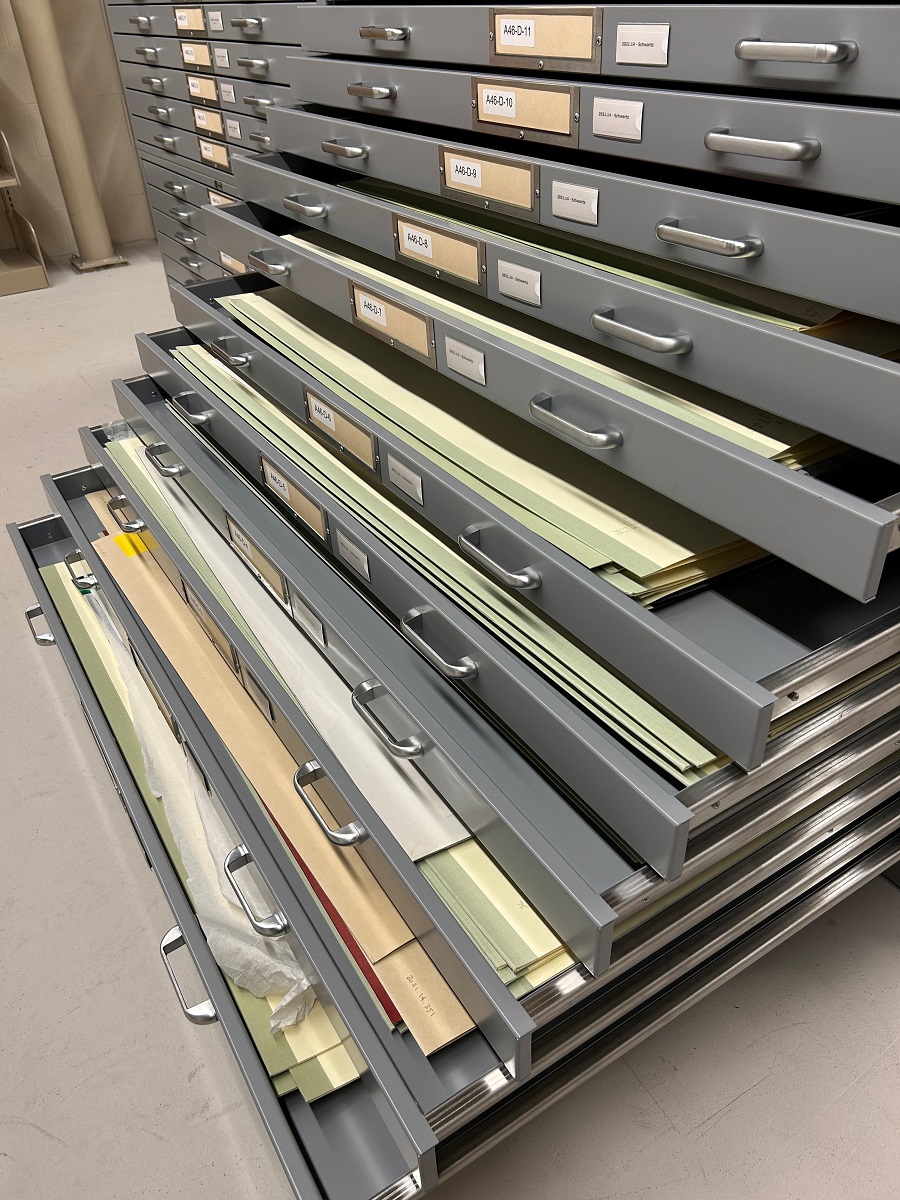 Large flat filing cabinet opened in a waterfall fashion to show flat folders and papers inside