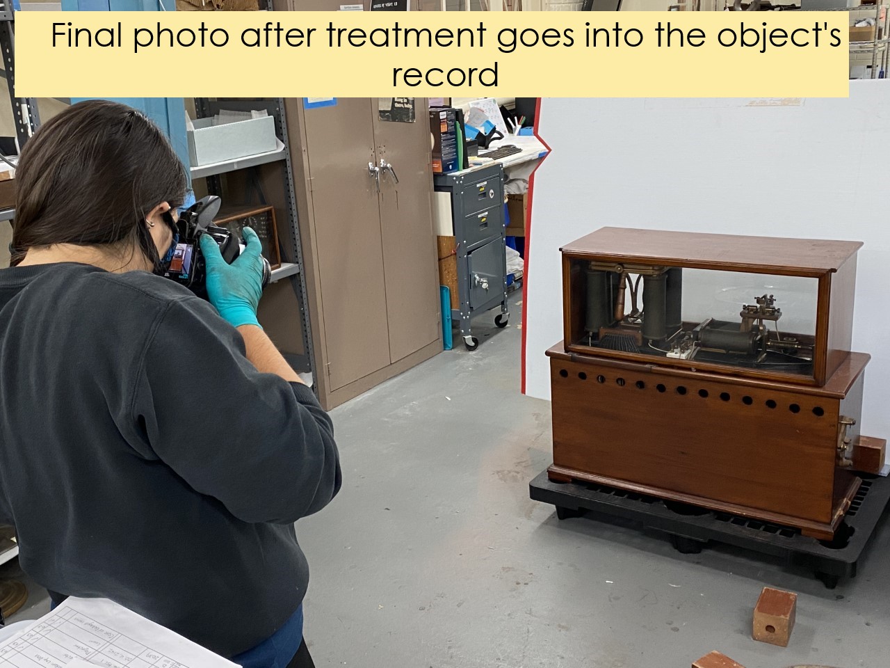 Final conservation photography for an artifact Person in gloves photographing a wood cabinet with machinery inside