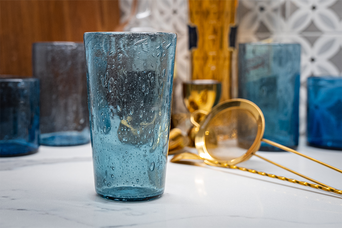 Pint glass created from recycled glass. In the background, you can see the variation that occurs, even when using one color of leftover glass. / Image by The Henry Ford