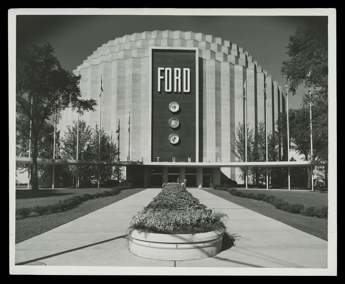 Crenellated round building with tiered top with large "FORD" sign
