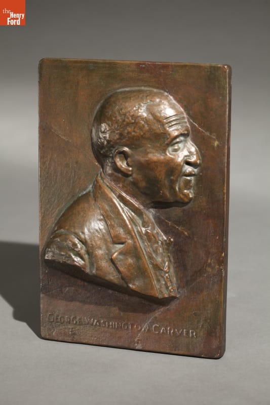 Brown plaque with relief of man's profile and text