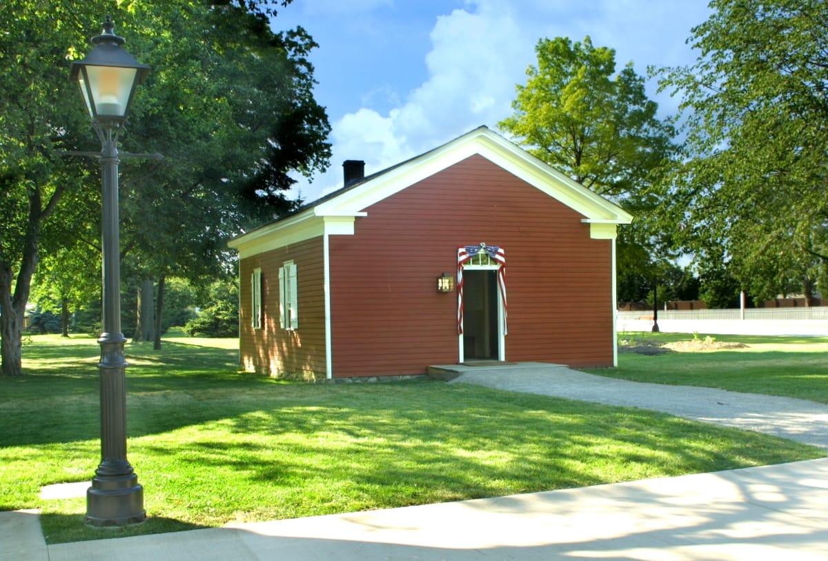 Dr. Howard's Office Small dark red wooden building on a large lawn with a streetlamp in front