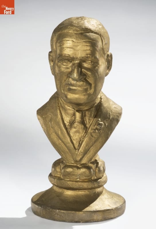 Gold sculpture of man's face and partial torso