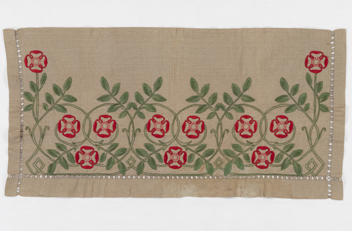 Beige textile embroidered with green and red floral pattern