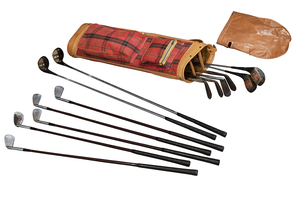 Set of Wilson Golf Clubs, circa 1955 Golf clubs lying next to red plaid golf bag and brown leather bag cover