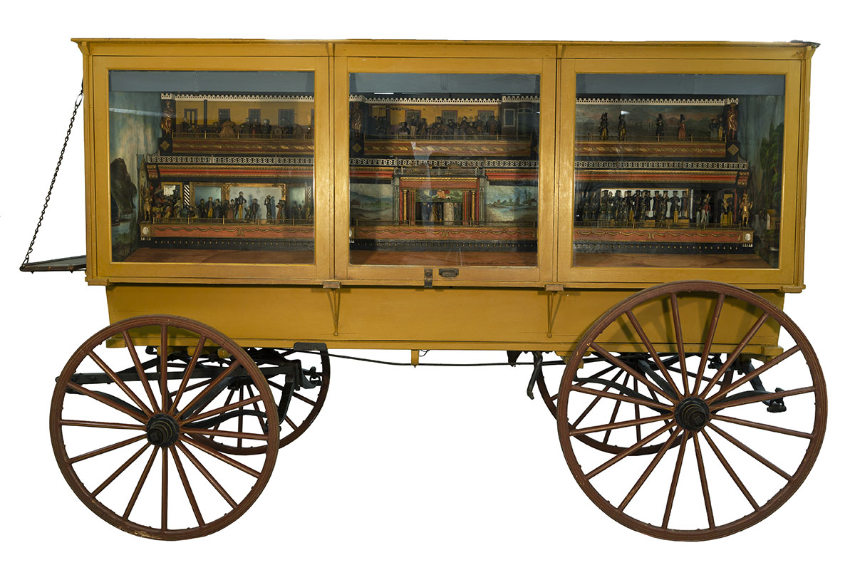 Yellow wagon with glass windows on side, behind which are small dioramas