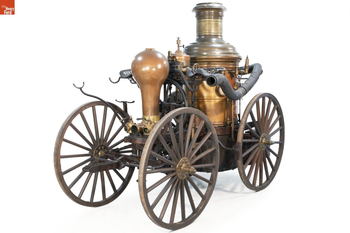 Machinery and copper tank mounted atop a four-wheeled wooden wagon