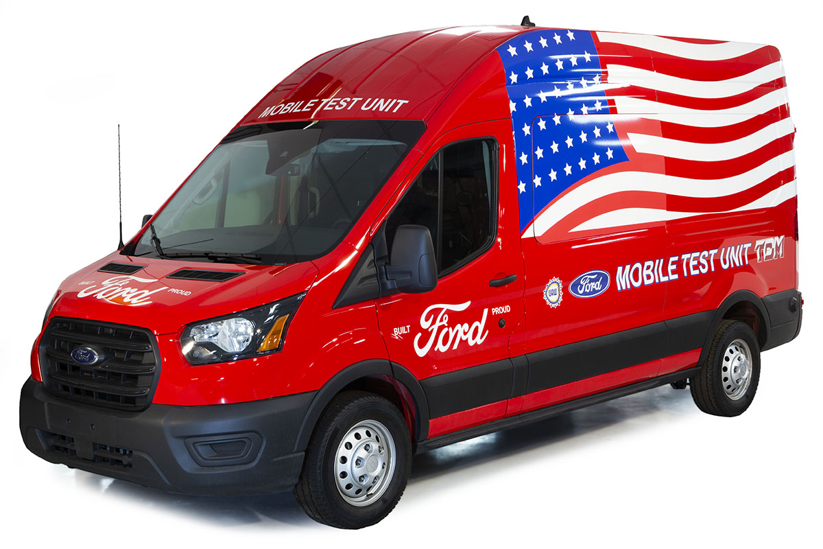 Tall red van with text and large waving American flag on side