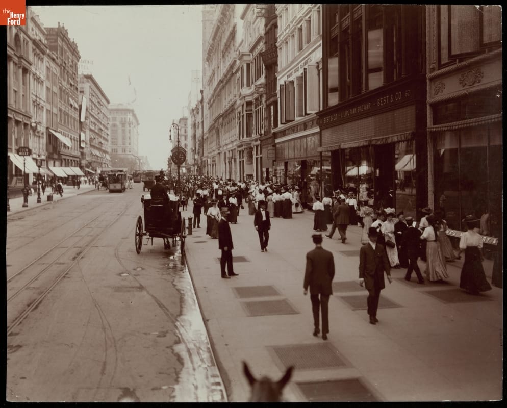 Street scene, with tall buildings, carriages, and pedestrians