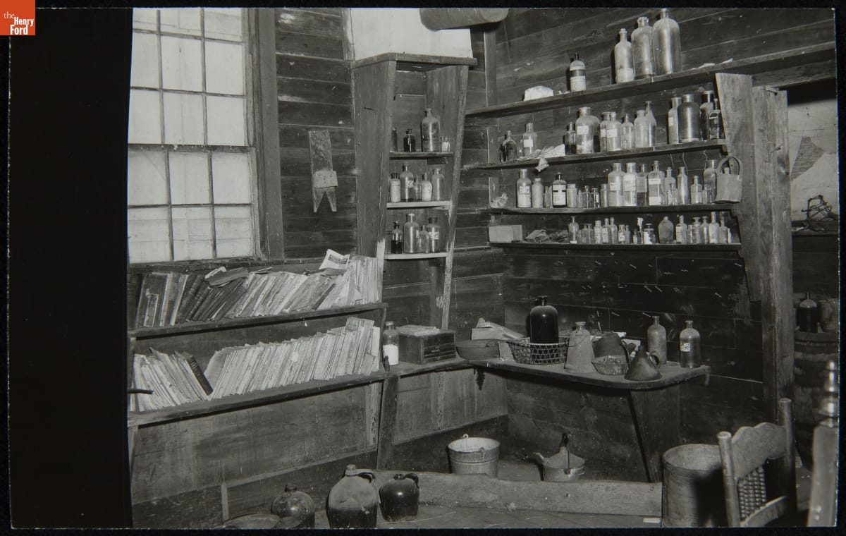 Dr. Howard's Office at Its Original Site, Tekonsha, Michigan, March 1956 Room interior containing shelves and tables covered in books, bottles, jugs, and other items