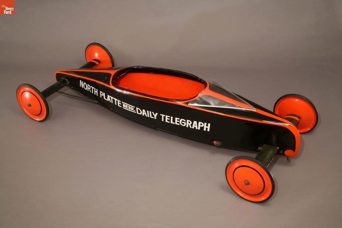1939 Soap Box Derby Car Teardrop-shaped black-and-orange wheeled vehicle with text along side