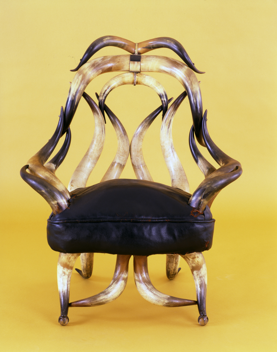 Chair with black leather seat cushion and back, arms, and legs made out of steer horns