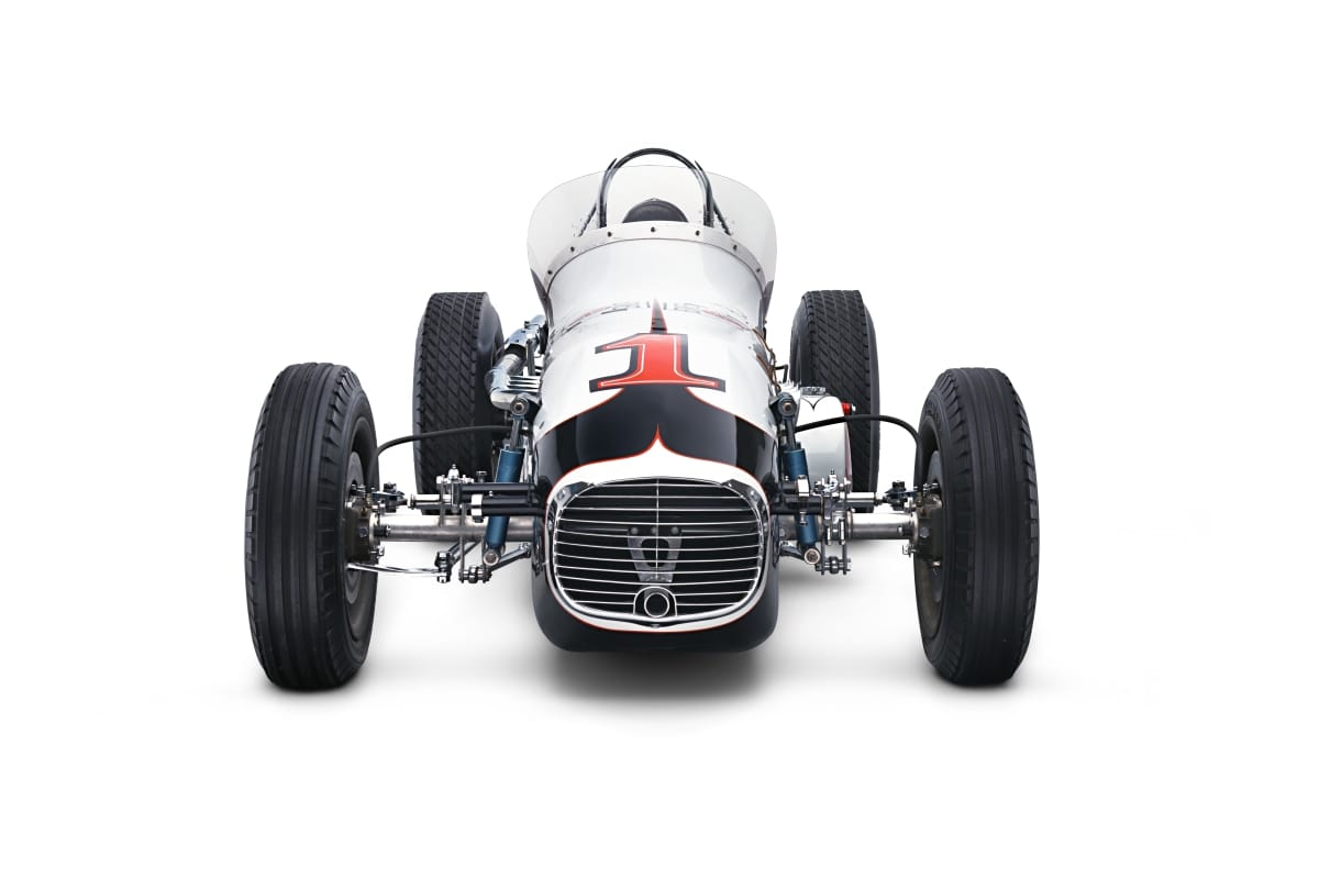 Head-on view of narrow black-and-white race car with open cockpit and large wide-set tires