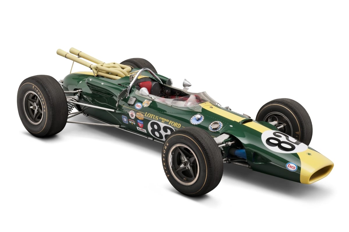 Long, low, torpedo-shaped green and yellow race car with large tires and open cockpit