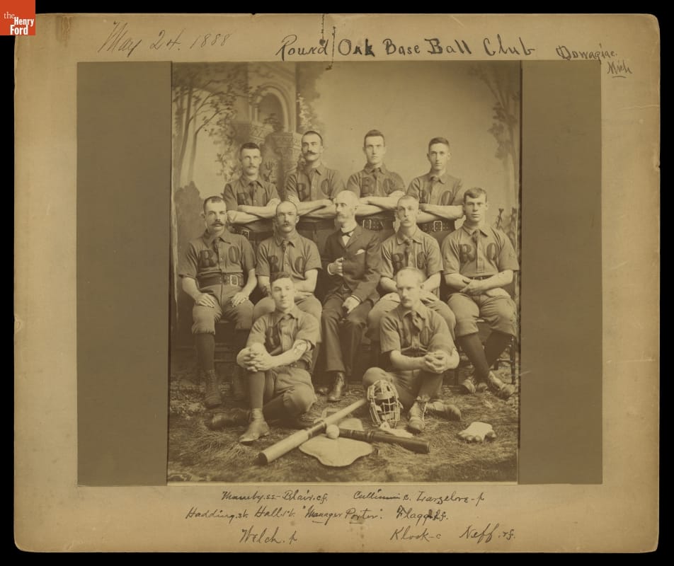 Posed photo of group of men wearing early baseball uniforms; also contains handwritten text